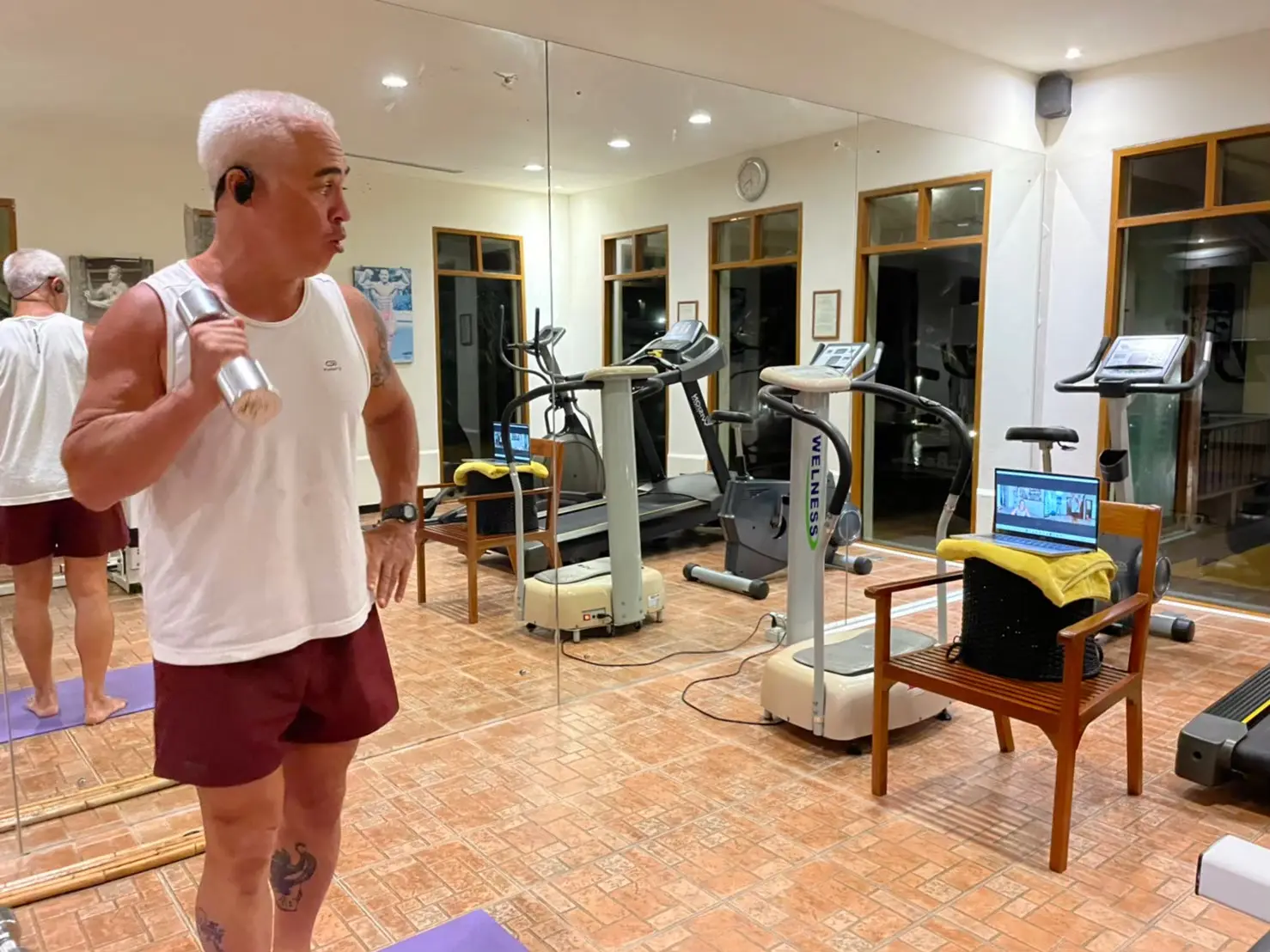 Client performing dumbbell strength training exercise with remote video coaching from personal trainer