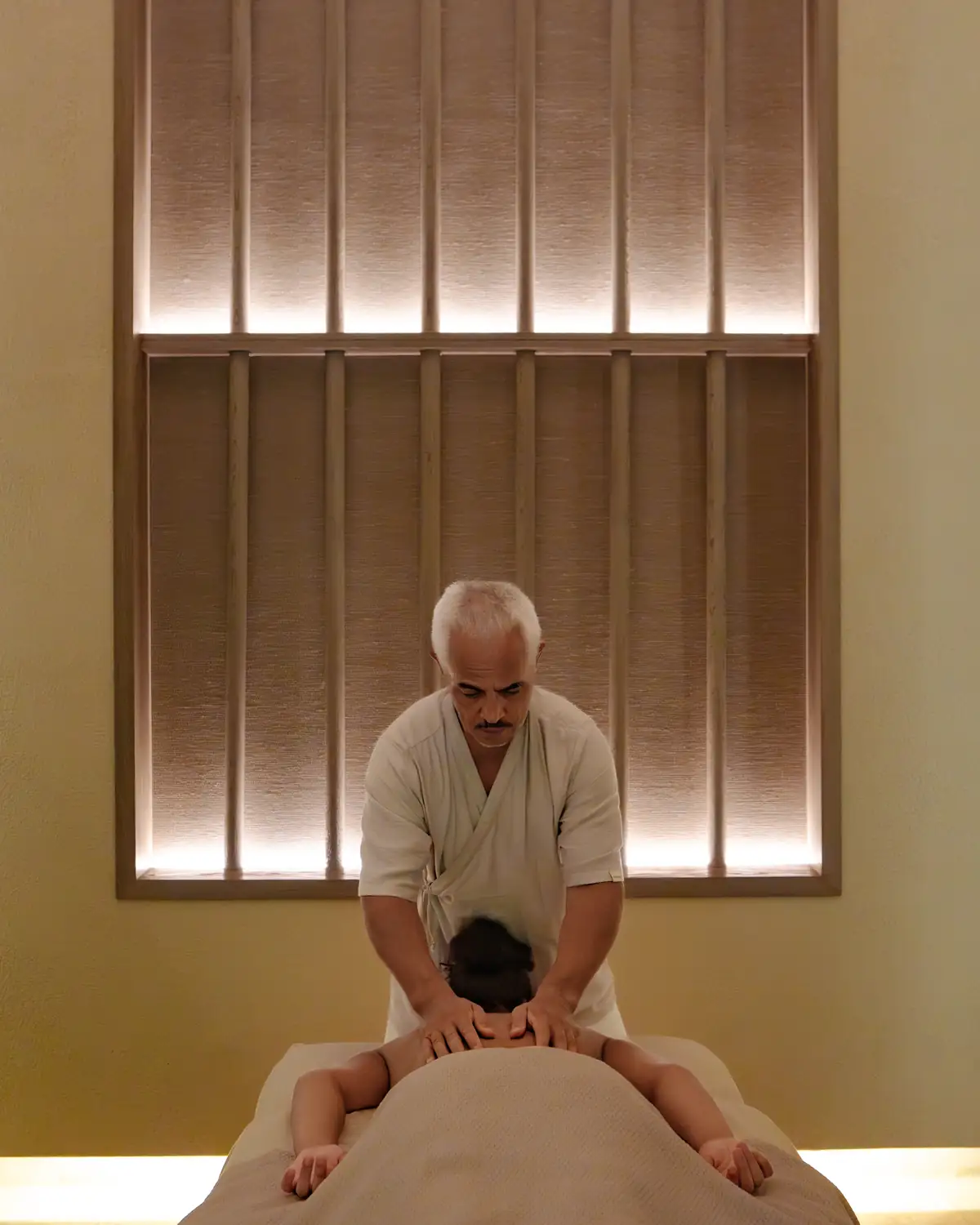 Karol Hasegawa performing therapeutic bodywork in an elegant luxury spa at JOALI BEING Maldives