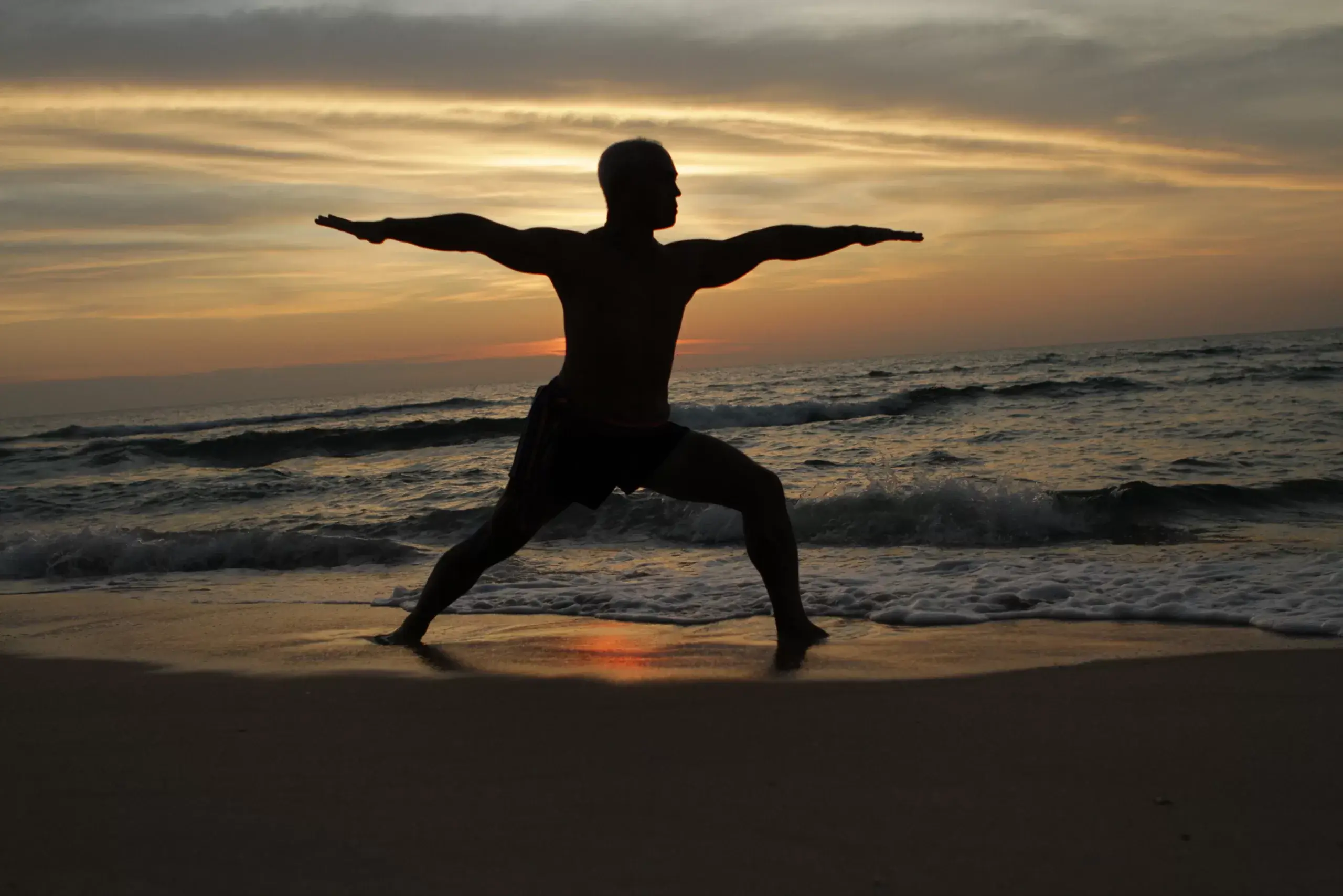 Karol Krauser warrior pose silhouette at sunset on Phuket beach Thailand